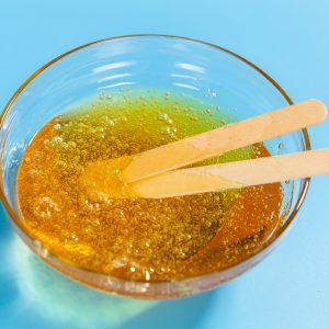 Depilation and beauty concept - close-up of sugar paste or honey wax for hair removing spatula with